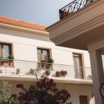 Traditional Greek house facade with potted plants and balcony details.