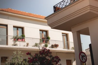 Traditional Greek house facade with potted plants and balcony details.