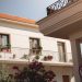 Traditional Greek house facade with potted plants and balcony details.