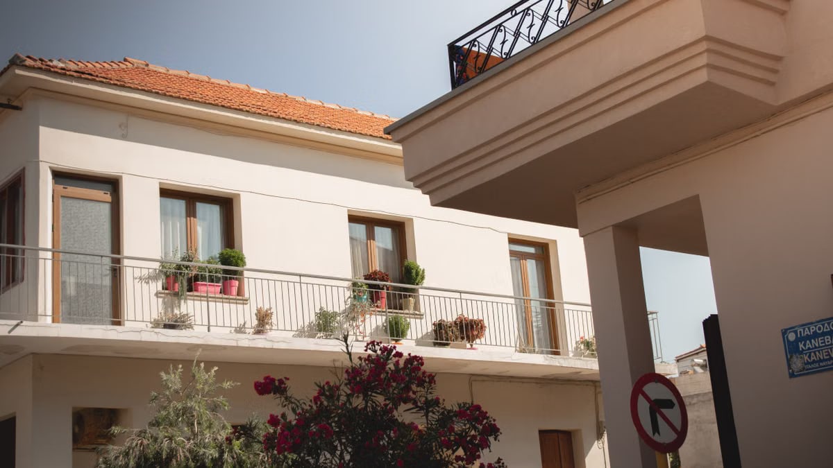 Traditional Greek house facade with potted plants and balcony details.